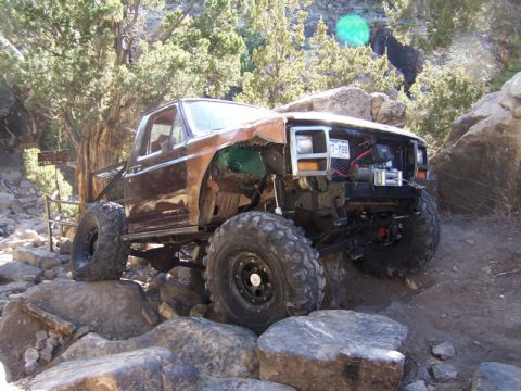 1981 Ford Bronco - This heavily modified SUV, possibly a Ford Bronco, is shown tackling a rocky trail. The license plate indicates a year of 1988.