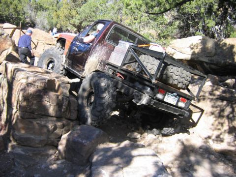 1981 Ford Bronco - Custom pickup truck tackling a difficult off-road obstacle on a sunny day.