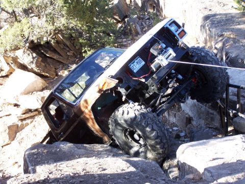 1981 Ford Bronco - This heavily modified off-road vehicle navigates a challenging rocky terrain, displaying a winch and a license plate.