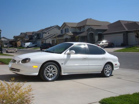 1995 Ford Taurus - This white 1995 Ford Taurus sedan is parked in a suburban driveway on a sunny day.