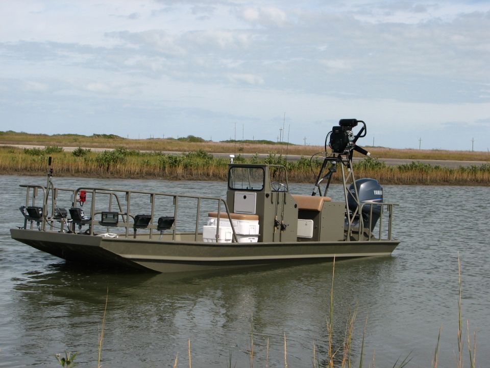 Flat-bottom boat with outboard motor and camera rig on water