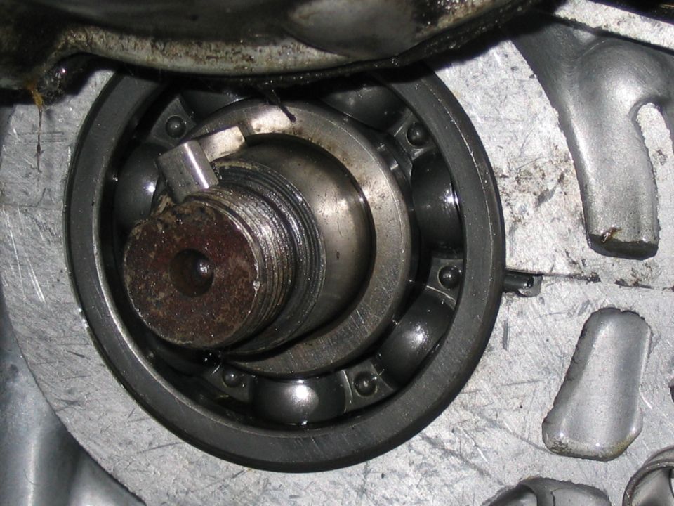 Close-up of a ball bearing and threaded shaft inside an aluminum engine case