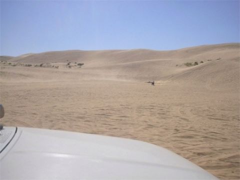 1993 Ford Bronco - View of desert dunes from inside a vehicle, with a distant figure on the sand.