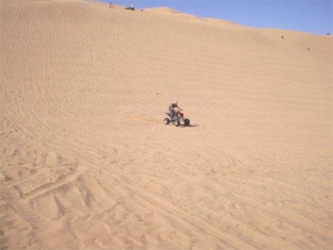 1993 Ford Bronco - A person rides an ATV across a vast sand dune under a clear blue sky.