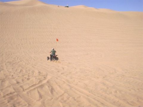 1993 Ford Bronco - An ATV navigates a sandy desert landscape with tire tracks visible on the dunes.