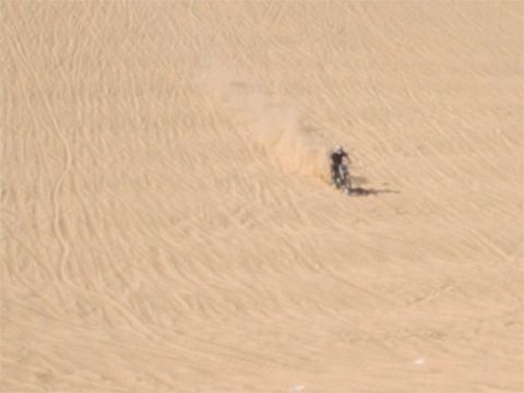 1993 Ford Bronco - A lone motorcycle navigates a sandy terrain, leaving tracks behind.