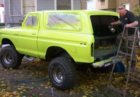 1978 Ford Bronco - Man sprays new lime green paint onto a 1978 Ford Bronco during a restoration project.