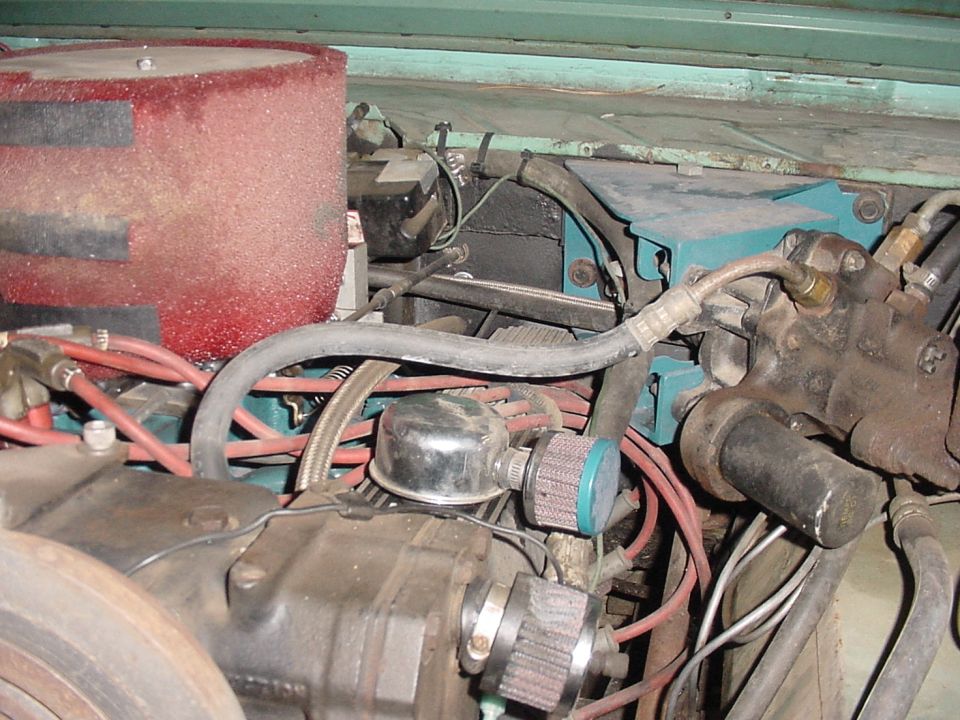 Engine bay with a large red air filter, hoses, and engine components. Some blue and black boxes are visible