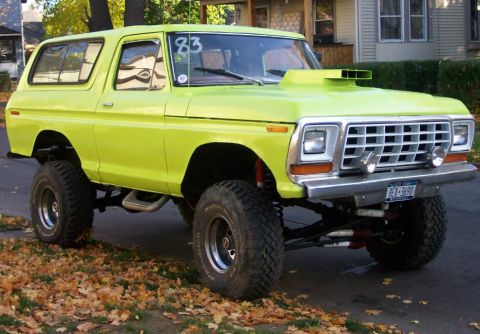 1978 Ford Bronco - A lifted 1978 Ford Bronco in a bright green paint job sits on a street with fallen leaves.