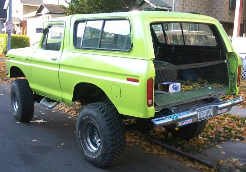 1978 Ford Bronco - This lifted SUV is parked on a street with fallen leaves scattered around.