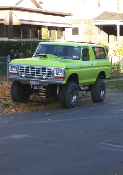 1978 Ford Bronco - This lifted SUV features a distinctive lime green paint job and an aftermarket hood scoop, with its grille clearly visible.