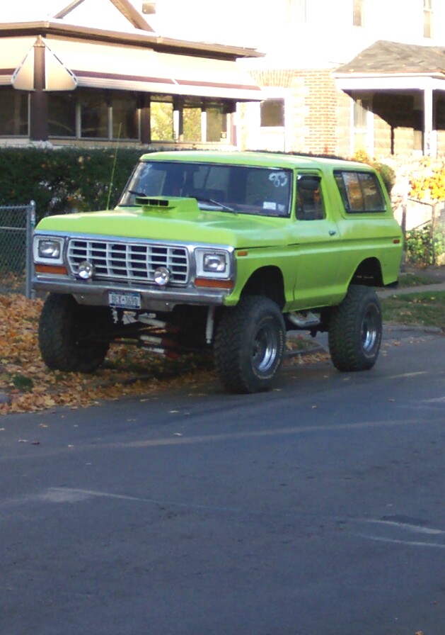 Lime green lifted SUV, 3/4 front view, with aftermarket hood scoop and prominent grille