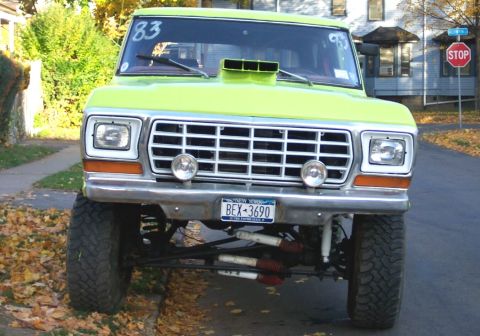 1978 Ford Bronco - This modified pickup truck features a prominent hood scoop and lifted suspension, parked on a residential street.