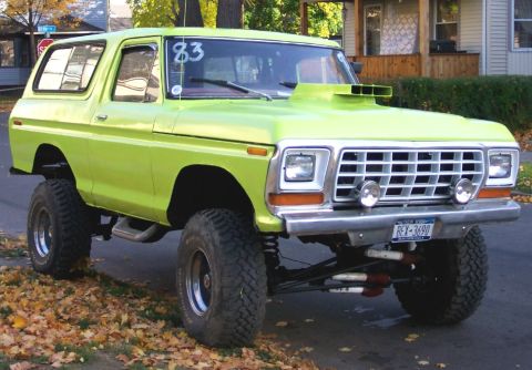 1978 Ford Bronco - A lime green 1978 Ford Bronco is parked on a street with fallen leaves.