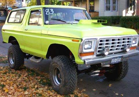 1978 Ford Bronco - A lime green 1978 Ford Bronco with a hood scoop and lifted suspension sits on a street with fallen leaves.