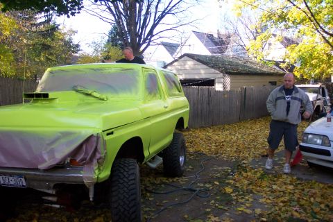 1978 Ford Bronco - A 1978 Ford Bronco is being spray-painted lime green in a yard with fallen leaves.