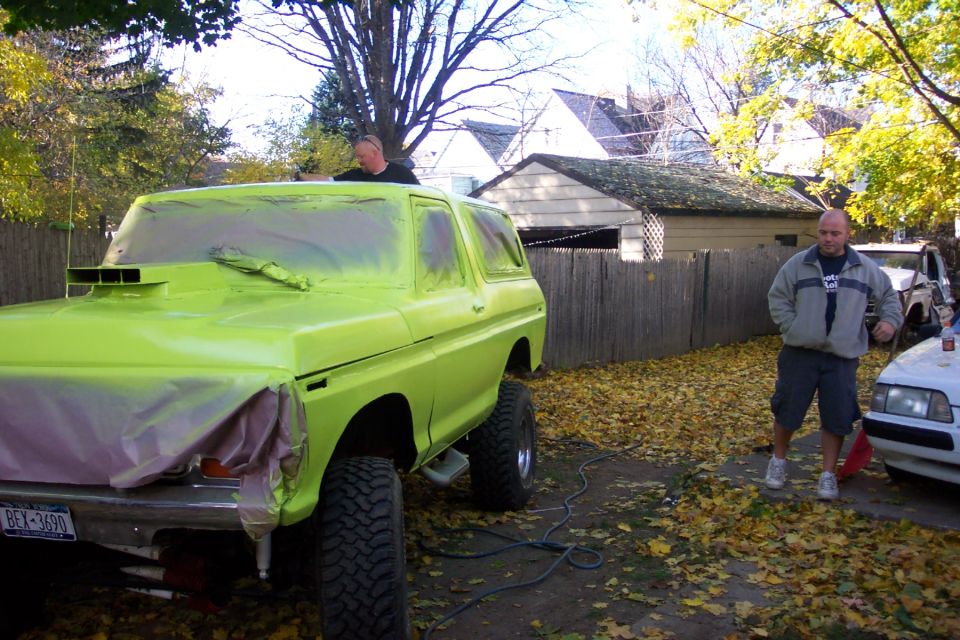 Lime green 1978 Ford Bronco with a hood scoop and large tires, partially masked for painting