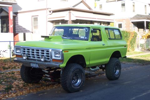 1978 Ford Bronco - A lifted, lime green 1978 Ford Bronco with a prominent hood scoop is parked on a residential street.