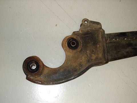 1996 Ford Bronco - This is a close-up view of a suspension control arm, showing its metal construction and rubber bushings.