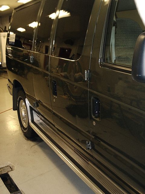 1996 Ford Bronco - This dark van features running boards and tinted windows, with a reflection of overhead lights on its surface.