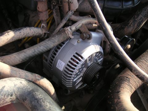1994 Ford Bronco - Overhead view of a newly mounted silver 12V 130A alternator, its parts label still attached, sitting in an engine bay before the serpentine…