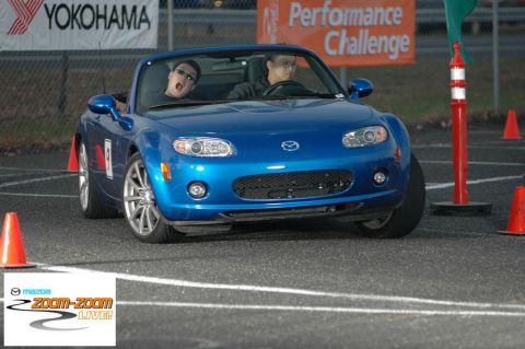 2001 Mercury Grand Marquis - A blue Mazda Miata convertible navigates a course marked by orange cones, with a Yokohama banner visible in the background.