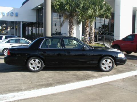 2000 Ford Crown Victoria - Side view of a black 2000 Ford Crown Victoria parked in front of a dealership.