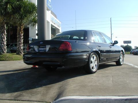 2000 Ford Crown Victoria - Rear view of a black 2000 Ford Crown Victoria parked outside a dealership with palm trees and a Ford sign.