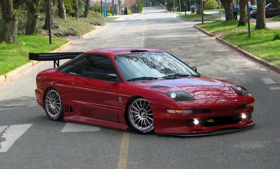 Red Ford Probe coupe with body kit, rear wing and lowered stance on a street