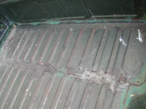 1973 Ford Ranchero - The interior of a truck bed shows a ribbed metal floor with signs of rust and dirt.