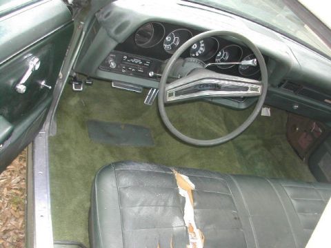 1973 Ford Ranchero - The interior of a 1973 Ford Ranchero shows green carpeting, a cracked seat, and dashboard instrumentation.
