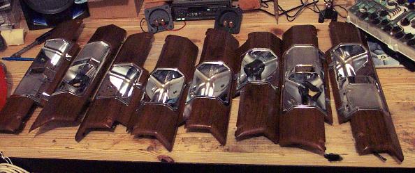 Several wood-grain interior trim pieces with chrome accents laid out on a wooden surface