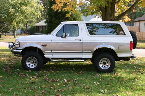 1994 Ford Bronco - 1994 Ford Bronco parked on grass with fall foliage in the background.