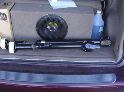 1979 Ford Bronco - A driveshaft is stored in the cargo area of a vehicle along with a speaker and a bottle of fluid.