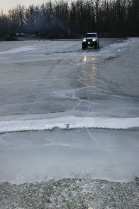 2003 Jeep TJ - Jeep TJ navigating an icy road during dusk, with tire tracks visible on the ice.