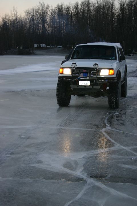 2003 Jeep TJ - A white SUV drives across a frozen body of water during dusk.