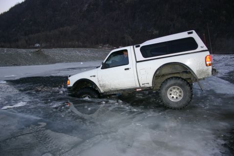 2003 Jeep TJ - Pickup truck is stuck in the ice, with the front wheel deep in the frozen water.