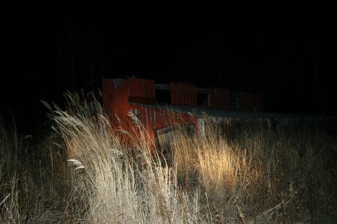 2003 Jeep TJ - An old, dilapidated red structure stands in overgrown dry grass under the dark night sky.