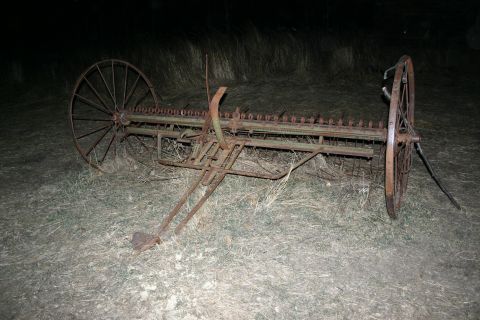 2003 Jeep TJ - This old farm implement sits in a field, its cutting bar and large spoked wheels showing significant rust.