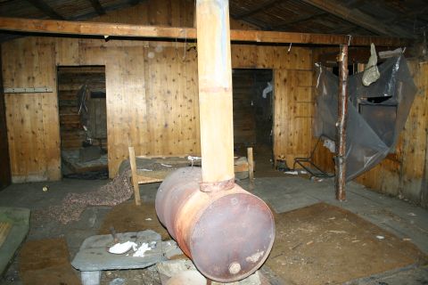 2003 Jeep TJ - The interior of a rustic wooden cabin features a barrel stove, wooden walls, and simple beds.