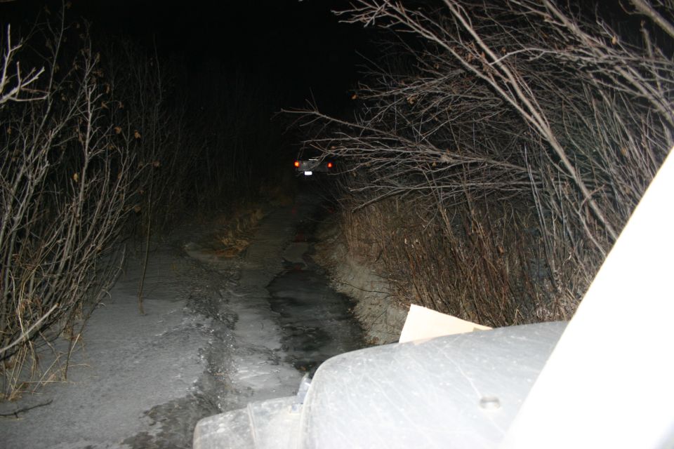 Jeep on a dirt road at night, with another vehicle in the distance