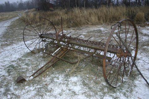 2003 Jeep TJ - An old, weathered farm implement rests on a snow-dusted field, hinting at past agricultural use.