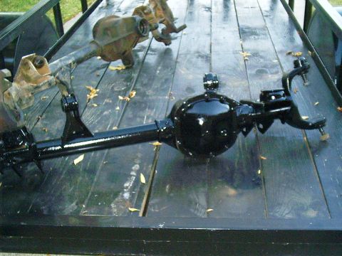 1986 Ford Bronco - A freshly painted black axle is shown alongside a rusty, older axle on a trailer.
