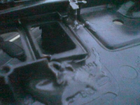 1990 Ford Bronco - dark interior shot of a freshly painted floor pan with a rectangular opening, drain hole and embossed factory markings.