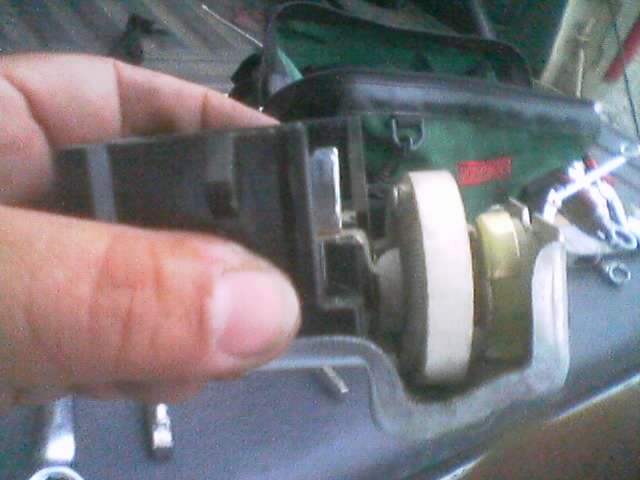 Hand holding a black switch housing with a white gear and brass component