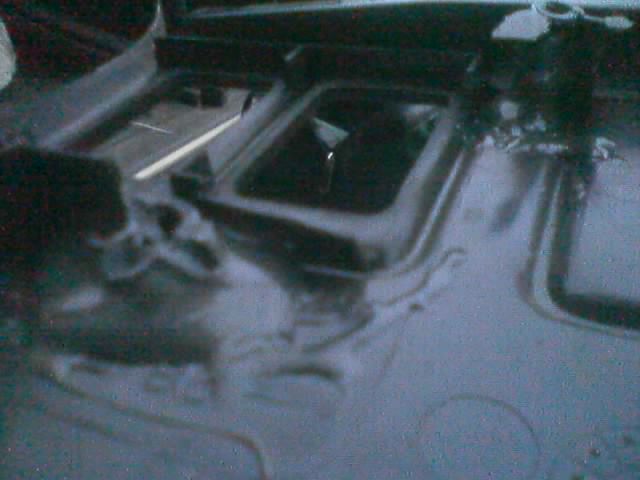 Dark interior shot of a black-painted floor pan with openings and seams