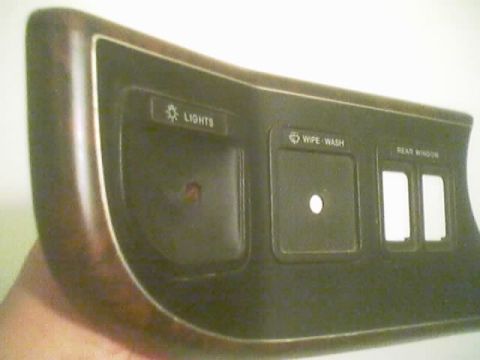 1990 Ford Bronco - curved black dashboard switch bezel with engraved LIGHTS, WIPE-WASH and REAR WINDOW labels, held in a hand against a white background.