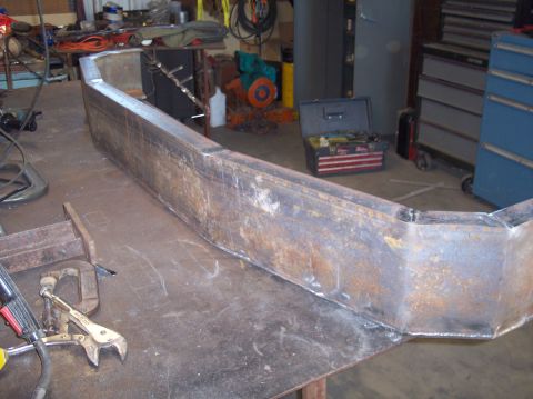 1979 Ford Bronco - A custom-fabricated metal bumper is shown on a workbench in a workshop setting.