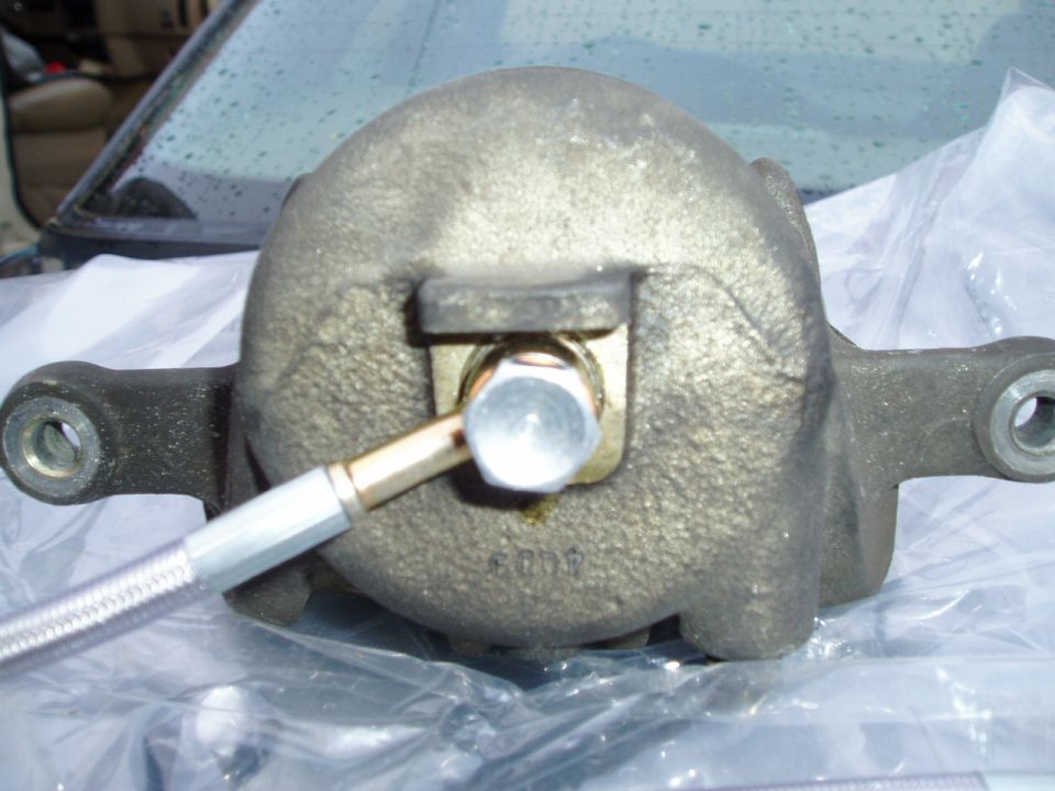 Brake caliper with attached brake line, resting on plastic