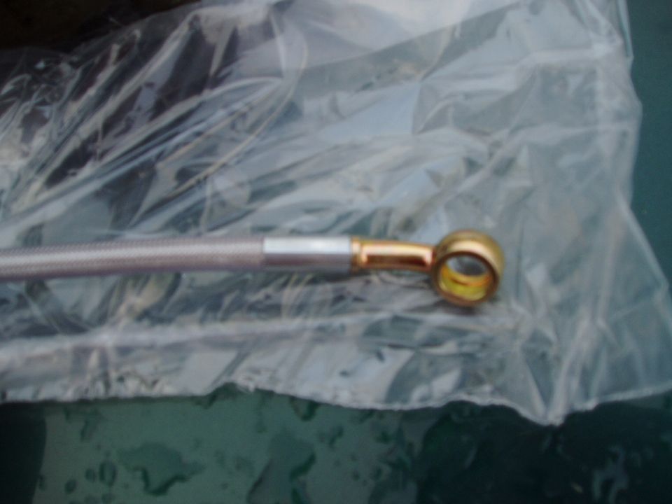 Close-up of a braided metal brake hose with a brass fitting